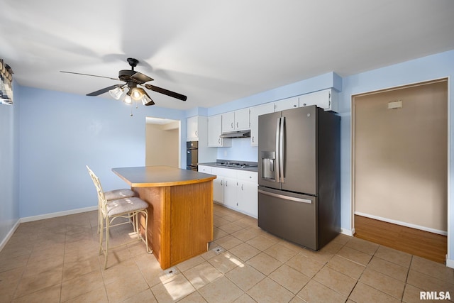 kitchen featuring appliances with stainless steel finishes, white cabinetry, a center island, and a breakfast bar area