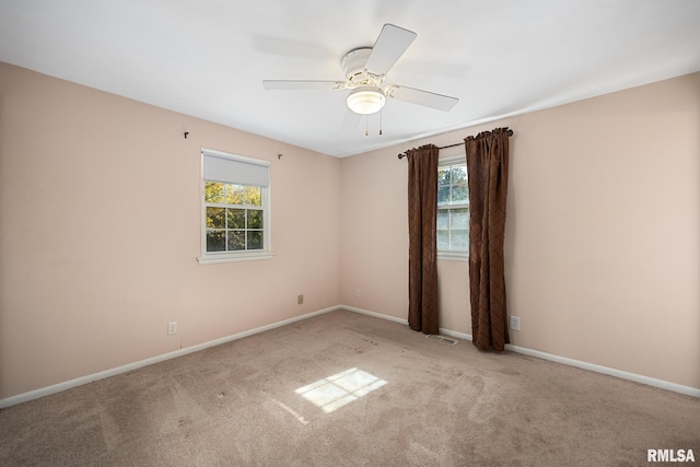 carpeted spare room featuring ceiling fan and a healthy amount of sunlight