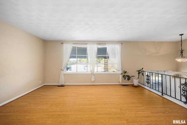 spare room with light hardwood / wood-style floors and an inviting chandelier