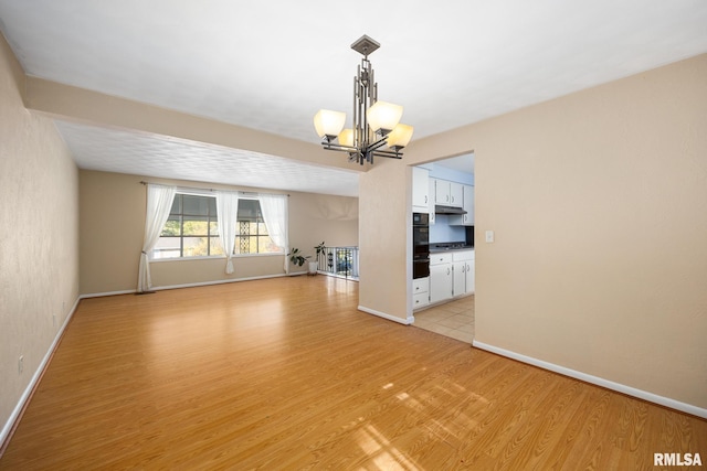 unfurnished living room with a chandelier and light hardwood / wood-style flooring