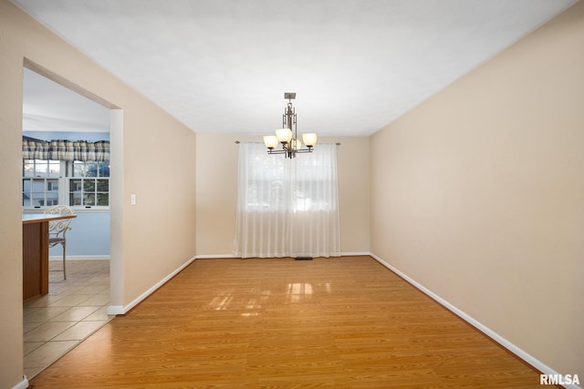 unfurnished dining area featuring a wealth of natural light, light hardwood / wood-style flooring, and a notable chandelier