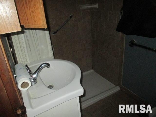 bathroom with a tile shower and vanity