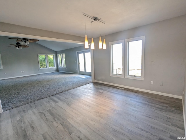 empty room with baseboards, visible vents, a ceiling fan, wood finished floors, and vaulted ceiling