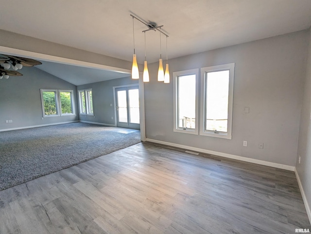 empty room featuring lofted ceiling, wood finished floors, visible vents, a ceiling fan, and baseboards