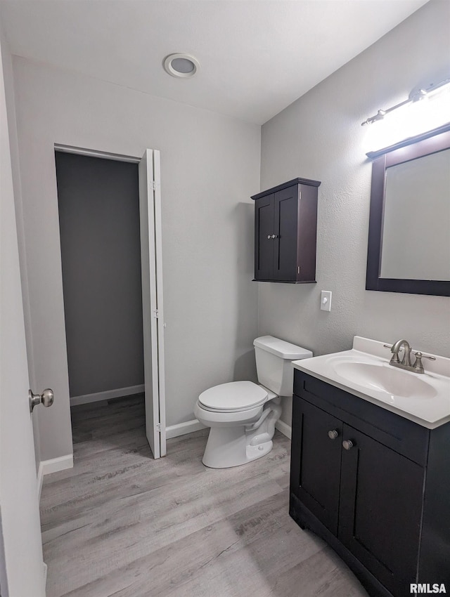 bathroom with baseboards, vanity, toilet, and wood finished floors