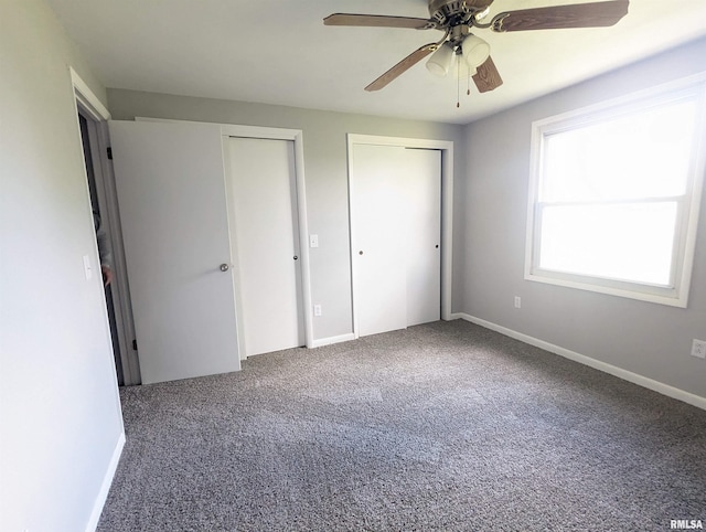 unfurnished bedroom with carpet floors, ceiling fan, baseboards, and two closets