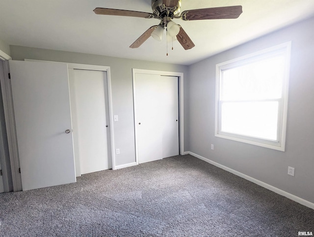 unfurnished bedroom featuring multiple closets, carpet flooring, baseboards, and a ceiling fan