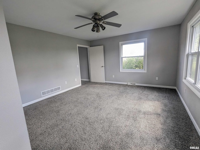 carpeted empty room with plenty of natural light, baseboards, visible vents, and ceiling fan