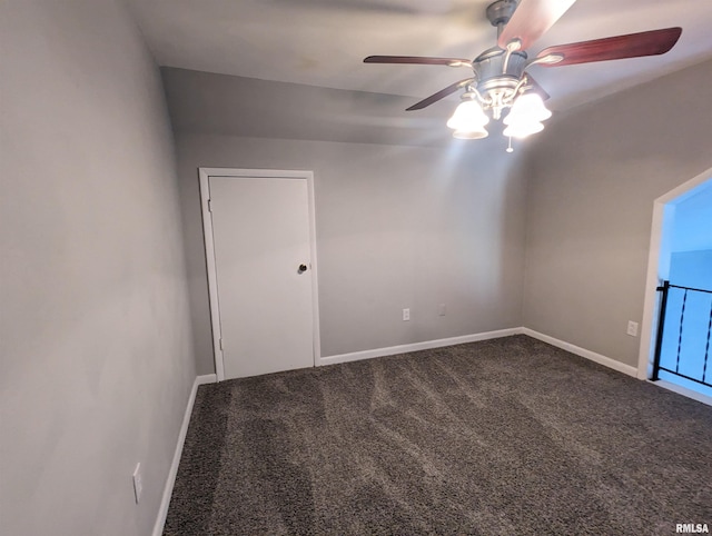 carpeted spare room featuring baseboards and a ceiling fan