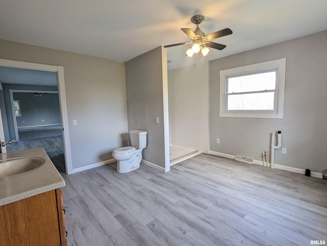 unfurnished room with baseboards, visible vents, a ceiling fan, wood finished floors, and a sink