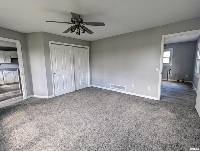 unfurnished bedroom with ceiling fan, visible vents, baseboards, a closet, and dark colored carpet