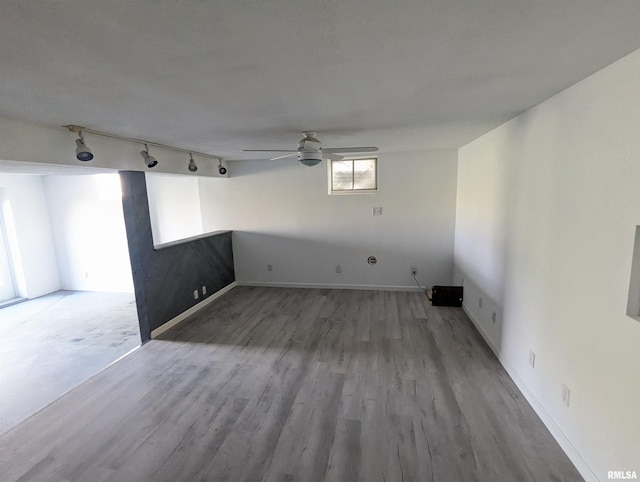 empty room featuring wood finished floors, a ceiling fan, and track lighting