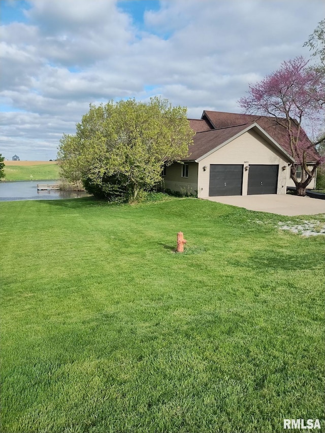 view of yard with a garage, driveway, and a water view