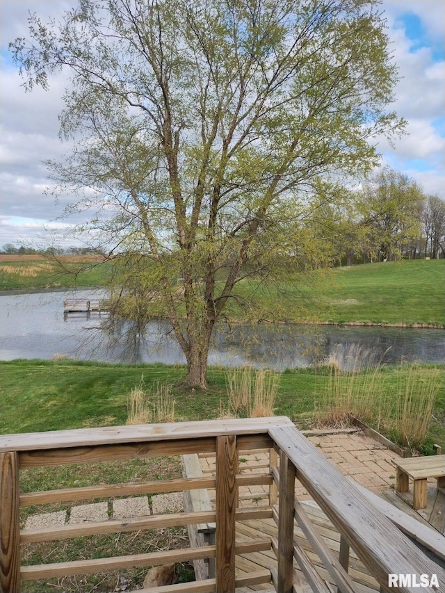 wooden terrace with a water view and a yard