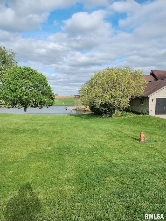 view of yard featuring an attached garage and a water view