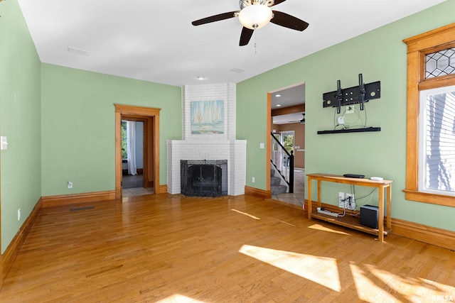 living room with hardwood / wood-style floors, ceiling fan, and a brick fireplace