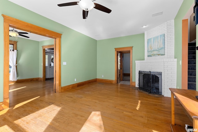 unfurnished living room featuring ceiling fan, light hardwood / wood-style flooring, and a brick fireplace