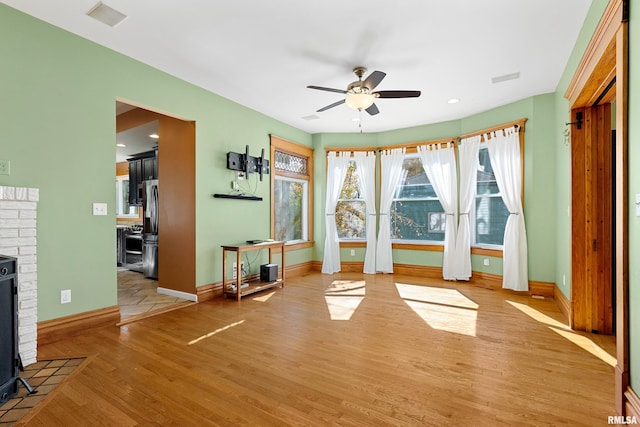 exercise room with ceiling fan and light wood-type flooring