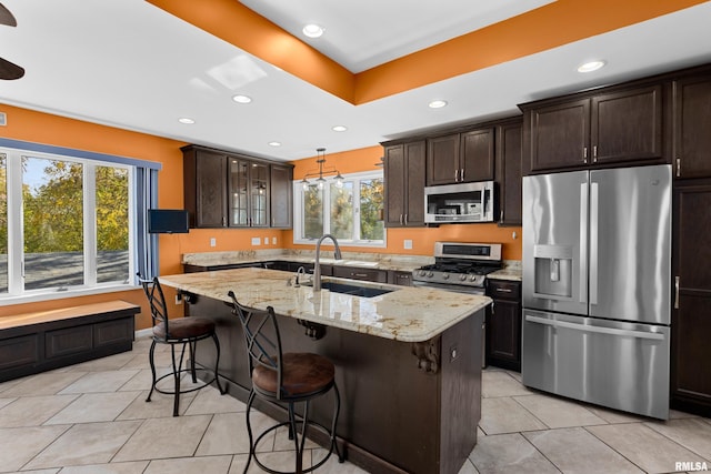 kitchen with a breakfast bar, stainless steel appliances, sink, and a center island with sink