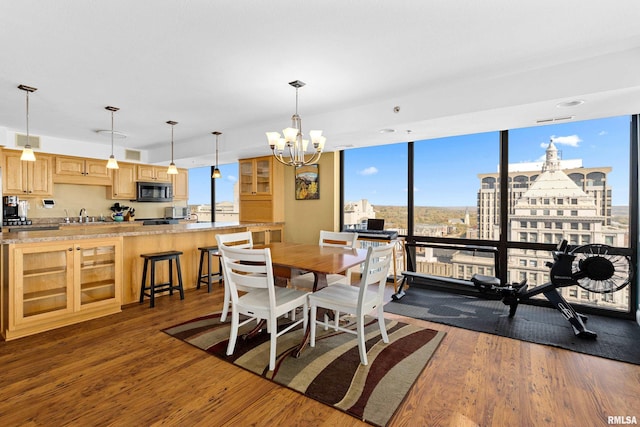 dining space with a notable chandelier, expansive windows, sink, and dark hardwood / wood-style floors