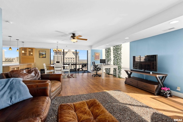 living room with ceiling fan with notable chandelier and light hardwood / wood-style floors