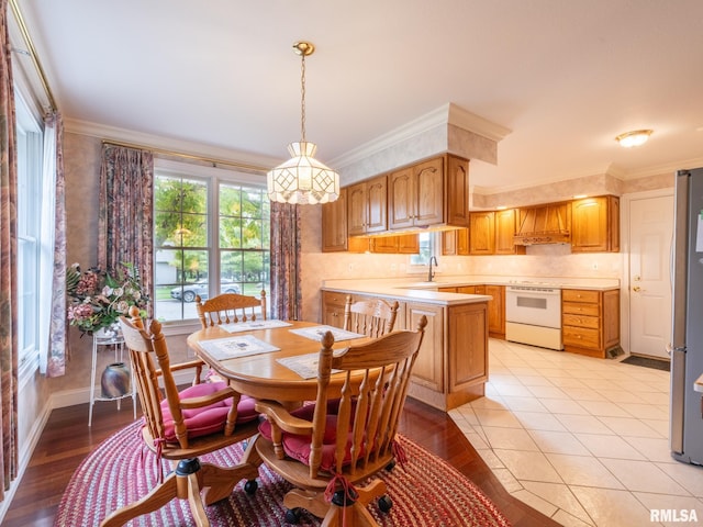 dining space featuring light wood-type flooring, crown molding, and sink