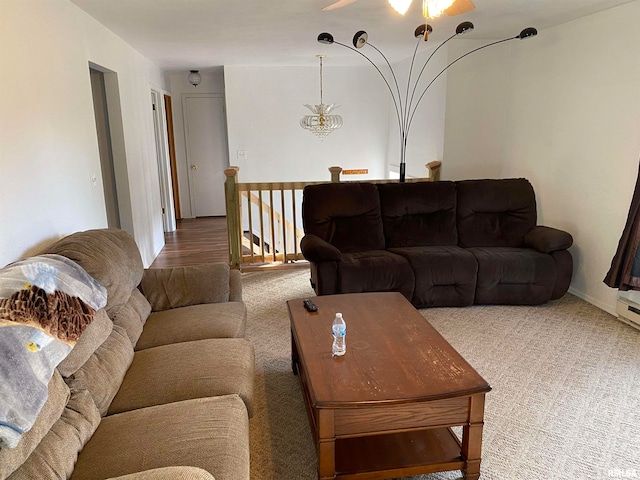 carpeted living room with ceiling fan with notable chandelier