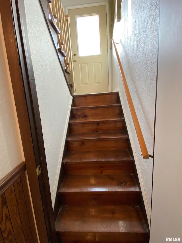 stairway featuring wooden walls