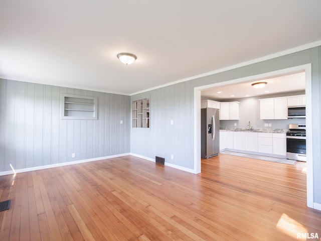 unfurnished living room with sink and light hardwood / wood-style flooring