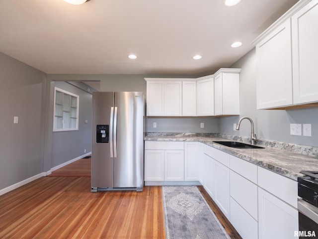 kitchen featuring white cabinetry, stainless steel fridge, sink, and light wood-type flooring