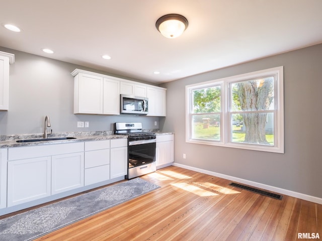 kitchen featuring white cabinetry, stainless steel appliances, sink, and light hardwood / wood-style flooring