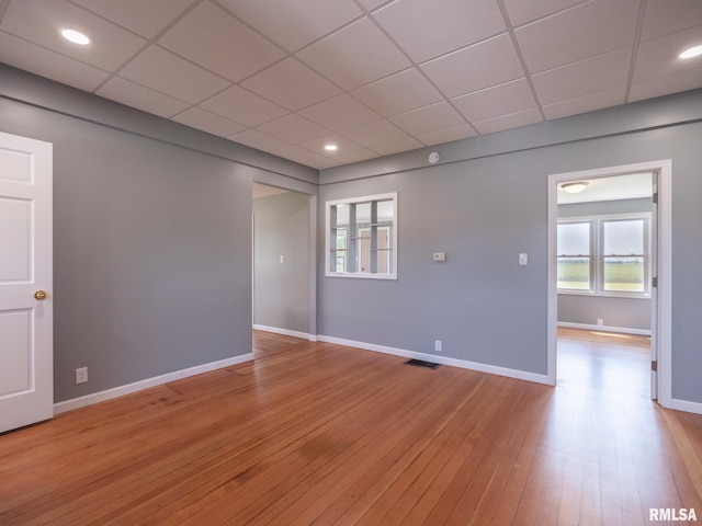 spare room with a paneled ceiling and light hardwood / wood-style floors