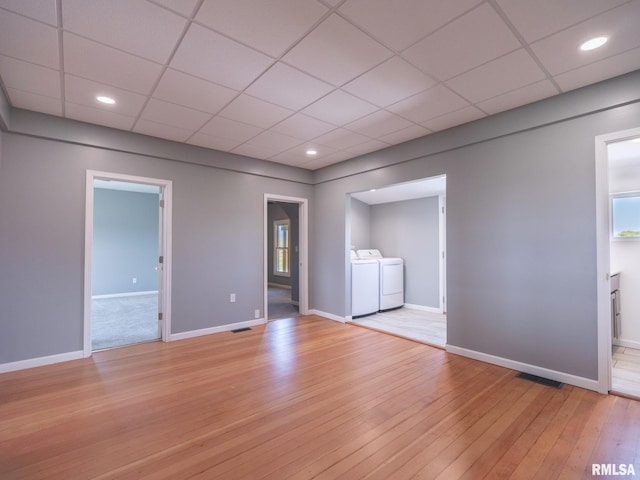 empty room with a paneled ceiling, washing machine and clothes dryer, and light wood-type flooring