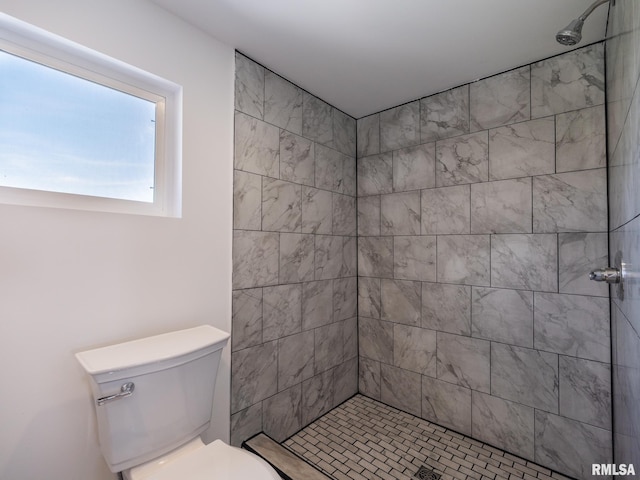 bathroom featuring tiled shower and toilet