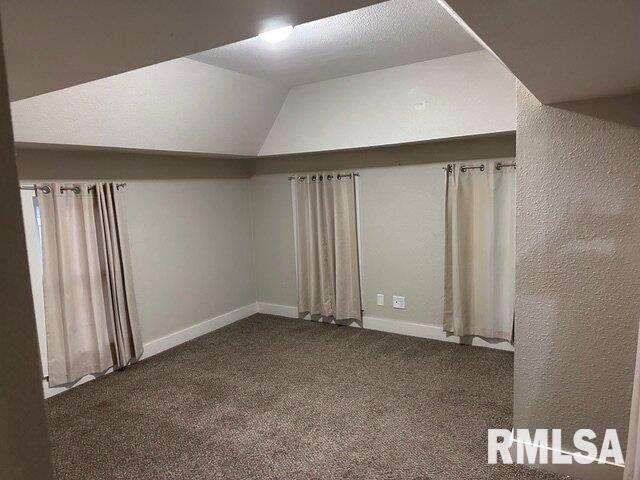 bonus room with vaulted ceiling and dark carpet