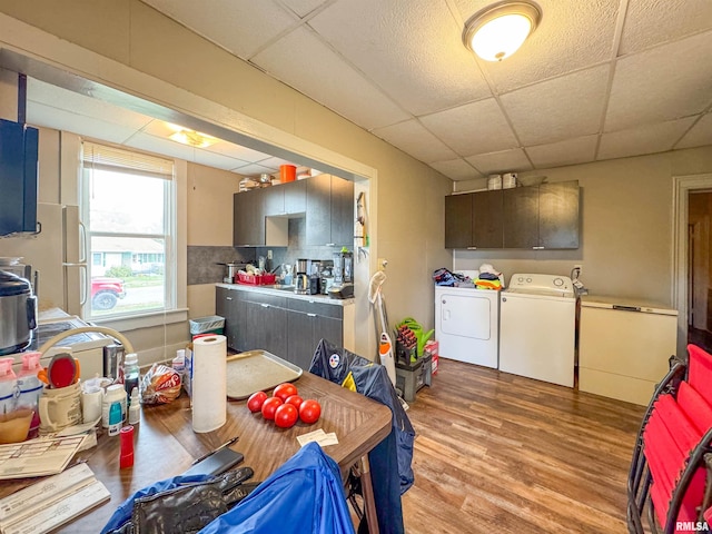 kitchen featuring decorative backsplash, a paneled ceiling, dark brown cabinetry, light wood-type flooring, and washing machine and clothes dryer