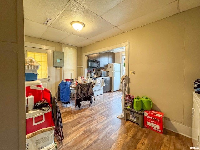 interior space with white fridge, a drop ceiling, and hardwood / wood-style floors