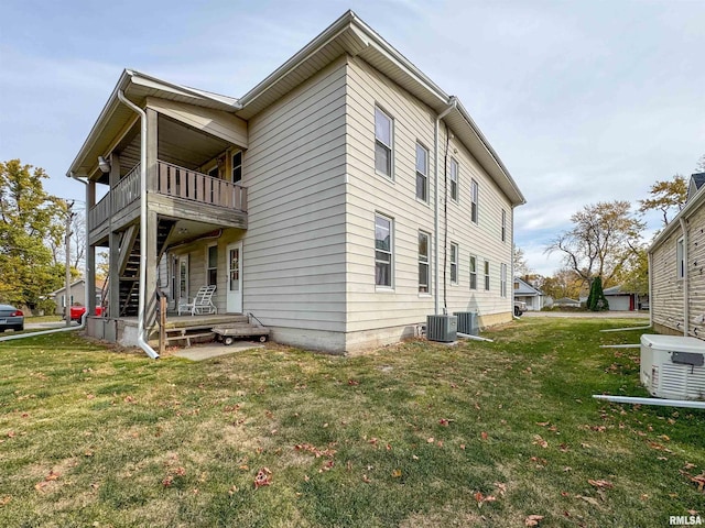 view of side of property featuring central air condition unit, a lawn, and a balcony