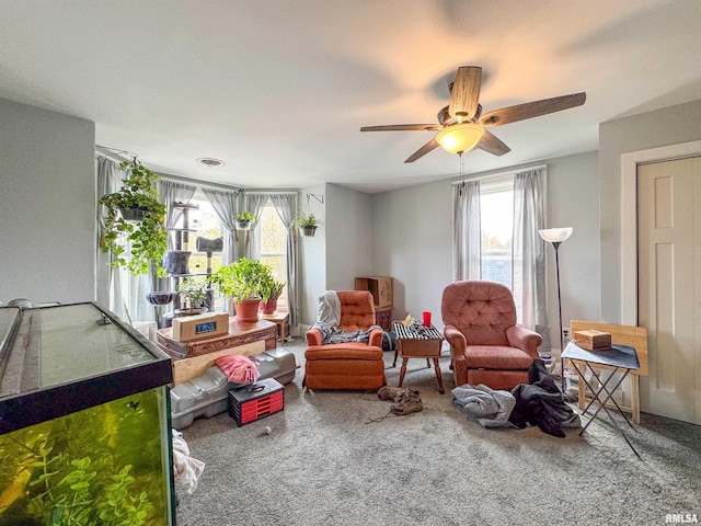 living area featuring carpet flooring, plenty of natural light, and ceiling fan