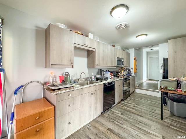 kitchen with light brown cabinetry, black appliances, sink, and light wood-type flooring