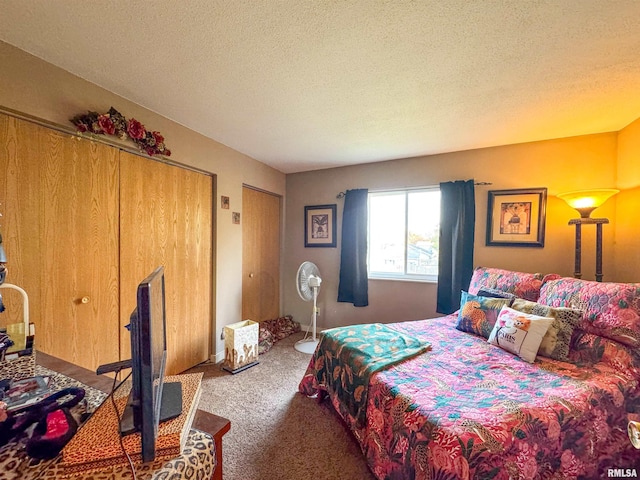 carpeted bedroom featuring a textured ceiling and multiple closets