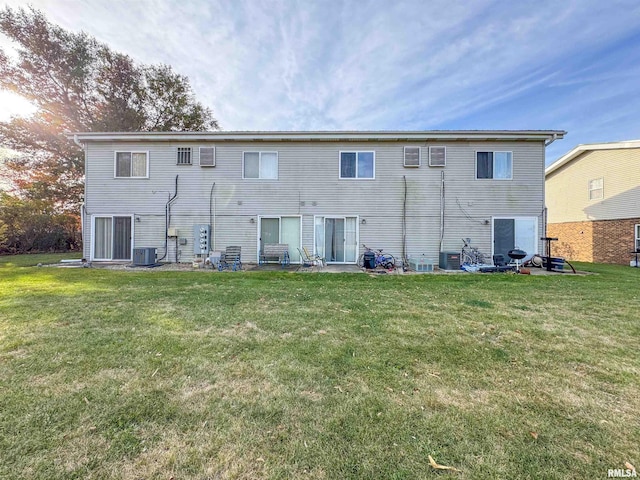 rear view of house featuring central AC and a lawn