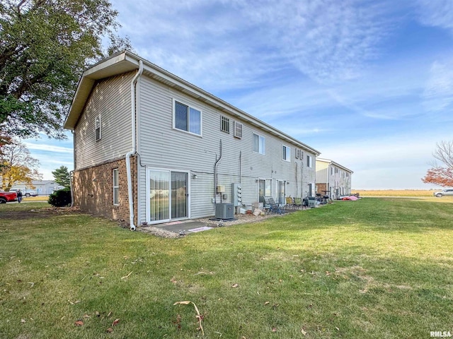 rear view of property with cooling unit and a yard