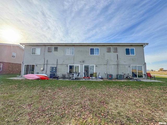 back of property with a lawn, a patio, and central AC