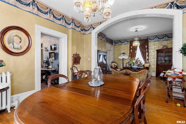 dining room with a notable chandelier, wood-type flooring, and radiator