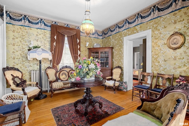 sitting room featuring radiator, wood-type flooring, and a notable chandelier