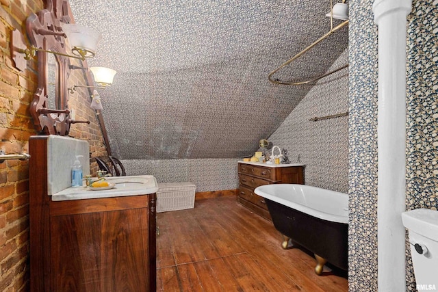 bathroom with vanity, a bath, vaulted ceiling, and hardwood / wood-style flooring