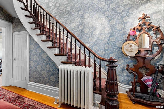 stairway with radiator and hardwood / wood-style floors