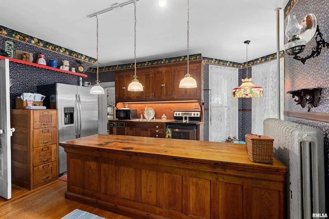 kitchen with hardwood / wood-style flooring, decorative light fixtures, butcher block counters, and stainless steel appliances