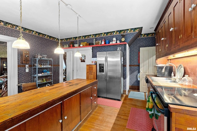 kitchen with hanging light fixtures, stainless steel fridge with ice dispenser, wooden counters, stove, and light hardwood / wood-style floors